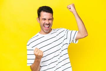 Young handsome man over isolated yellow background celebrating a victory