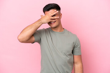 Young caucasian handsome man isolated on pink background covering eyes by hands and smiling