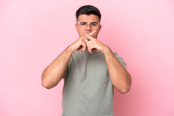 Young caucasian handsome man isolated on pink background showing a sign of silence gesture