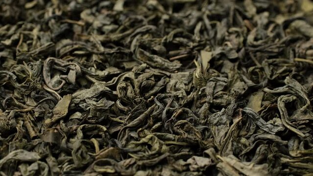 Heap of dried green tea leaves top view, rotation