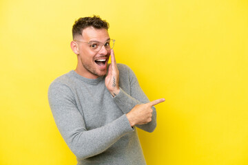 Young caucasian handsome man isolated on yellow background pointing to the side to present a...