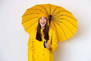 Young Brazilian woman with rainproof coat and umbrella isolated on white background with surprise facial expression