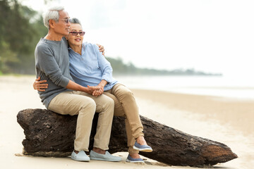 Asian Lifestyle senior couple hug and sitting on the beach happy in love romantic and relax time. ...