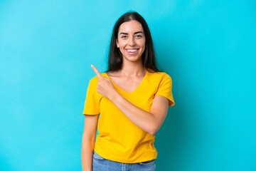 Young caucasian woman isolated on blue background pointing to the side to present a product