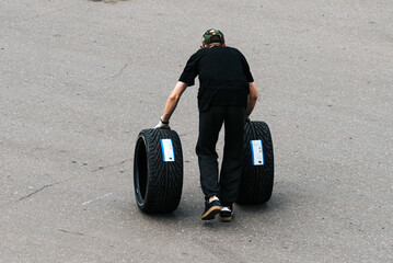 auto mechanic rolls wheels for a car. New tires for a racing car. tires for replacement. auto...