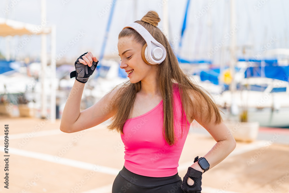 Wall mural Young pretty sport girl at outdoors listening music and dancing