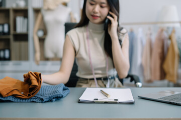 Female fashion designers use smart phones and use laptops with digital tablet computers to get orders from customers.