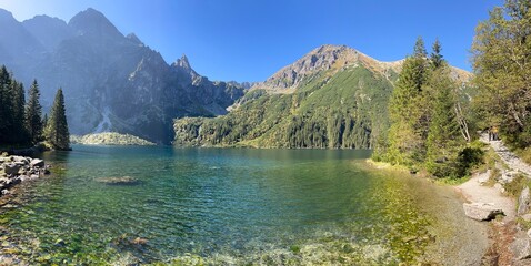 Pristine turquoise water of Morskie Oko Lake in Poland's Tatra National Park, surrounded by forest...