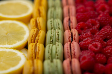 macaroons of different colors with raspberries and lemon