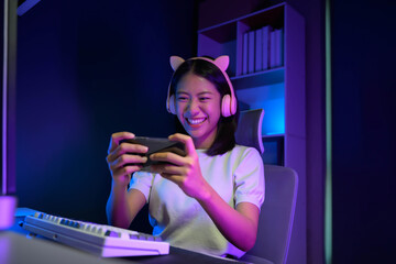 Naklejka premium Happy adorable Asian teen enjoying her game using smartphone, online game on smartphone.