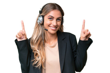 Telemarketer pretty Uruguayan woman working with a headset over isolated background pointing up a...