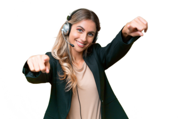Telemarketer pretty Uruguayan woman working with a headset over isolated background points finger at you while smiling