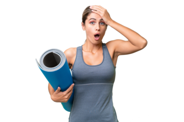 Pretty Young Uruguayan sport woman going to yoga classes while holding a mat over isolated background doing surprise gesture while looking to the side