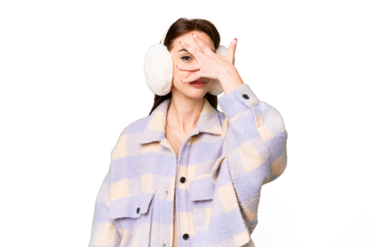 Young caucasian woman wearing winter muffs over isolated chroma key background covering eyes by hands and smiling