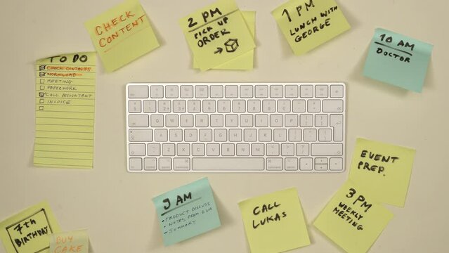 Sticky notes appearing around keyboard on office workplace. Daily schedule, to do list, time management, busy day concept. Top view, 4K stop motion animation.