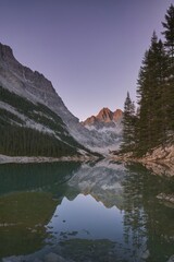 Grand mountain cliffs reflected in tranquil alpine lake at twilight 