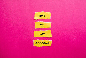 Time to say goodbye words written on yellow torn paper pieces with pink background. Conceptual...