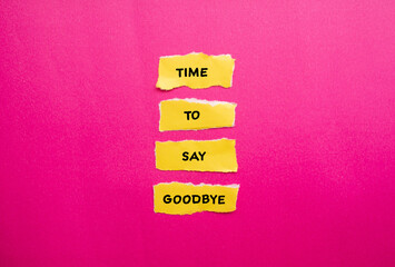 Time to say goodbye words written on yellow torn paper pieces with pink background. Conceptual symbol. Copy space.