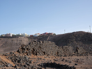 Barren hills and stone ruins on the edge of Las Palmas in the Canary islands, Spain. Houses in background