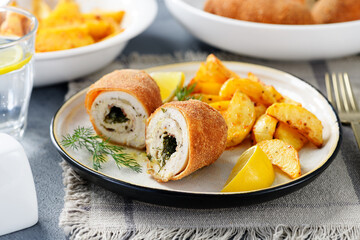 Chicken Kiev breast stuffed with butter, garlic and dill. Served with baked potato slices and fresh herbs.