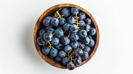 Grapes in a wooden bowl isolated on white background. Blue grapes with copy space for text. egetarian or healthy eating. Top view.