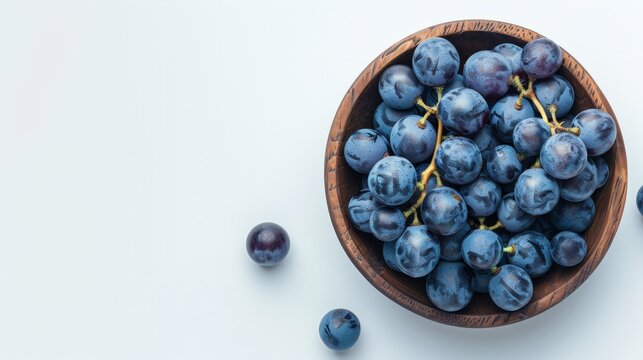Grapes in a wooden bowl isolated on white background. Blue grapes with copy space for text. egetarian or healthy eating. Top view.