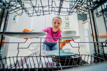 Young woman takes dishes out of the dishwasher machine