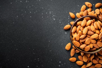 Poster Almond nuts in bowl at black background. © nadianb