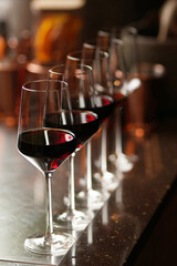 Wine glasses in a row on a bar counter, close-up.