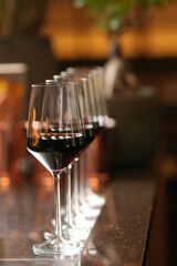 Wine glasses in a row on a bar counter, close-up.