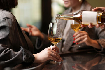 Close up of two female hands holding glasses of wine.