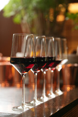 Wine glasses in a row on a bar counter, close-up.