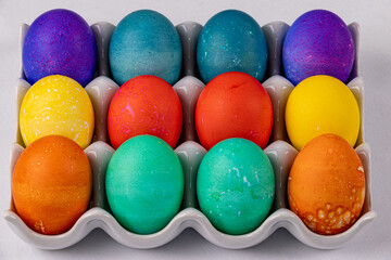 Close up of colored eggs in a ceramic dish purple green red yellow orange