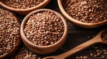 Fototapeta premium Buckwheat in a wooden bowl with a spoon on a wooden background. The concept of healthy eating. Buckwheat contains a large amount of vitamins and minerals.