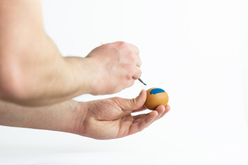 hands painting easter egg with paint brush isolated on white background. Decorating easter egg with...