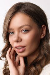 Fototapeta premium Beautiful young girl with fresh healthy skin. Woman advertise ear-rings. White background. Earrings closeup. Blond european woman with long hair with big lips, pretty smile. Cosmetology, scincare. 