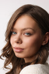 Fototapeta premium Beautiful young girl with fresh healthy skin. Woman advertise ear-rings. White background. Earrings closeup. Blond european woman with long hair with big lips, pretty smile. Cosmetology, scincare. 