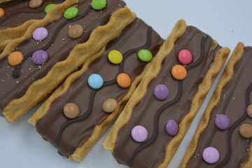 Sweets, delicious, interesting desserts, cookies with caramel, milk chocolate and small colored candies arranged on a white background.