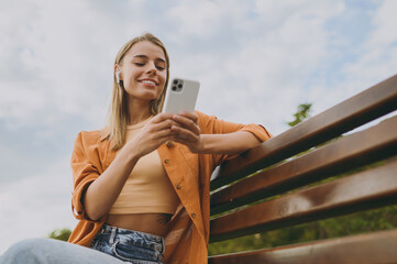 Bottom view young woman wear orange shirt casual clothes use mobile cell phone listen music in...