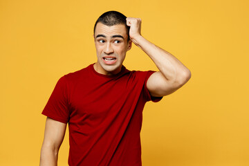 Fototapeta na wymiar Young shocked scared surprised sad middle eastern man he wearing red t-shirt casual clothes look aside scratch hold head isolated on plain yellow orange background studio portrait. Lifestyle concept.