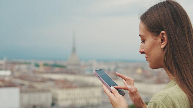 Close-up of a young woman looking at a photo on a mobile phone while standing on an observation deck