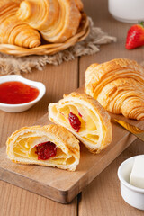 Freshly baked croissants with butter, strawberry jam and tea for breakfast