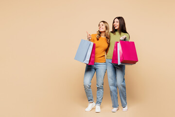 Full body young friends two women wear orange shirt casual clothes hold shopping paper package bags...