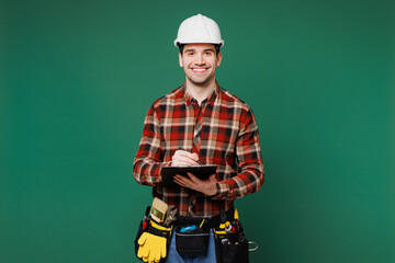 Young fun laborer man wear red shirt hardhat hat work write in clipboard with paper documents...