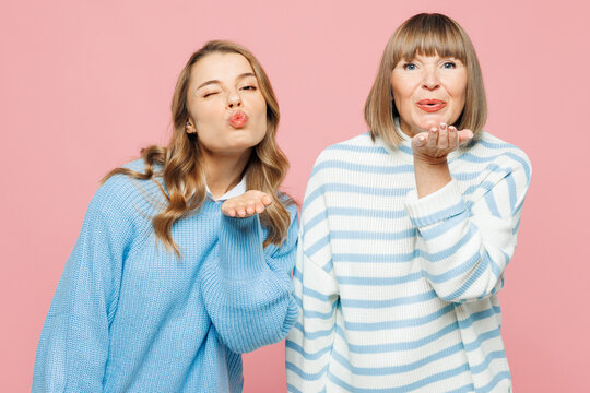 Elder happy lovely parent mom 50s years old with young adult daughter two women together wear blue casual clothes blow send air kiss isolated on plain pastel light pink background. Family day concept.
