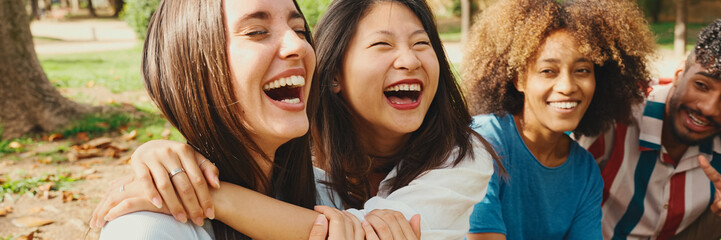 Happy multiethnic young people posing for the camera at picnic on summer day outdoors, Panorama....