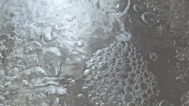 Surface of boiling water with many bubbles forming.