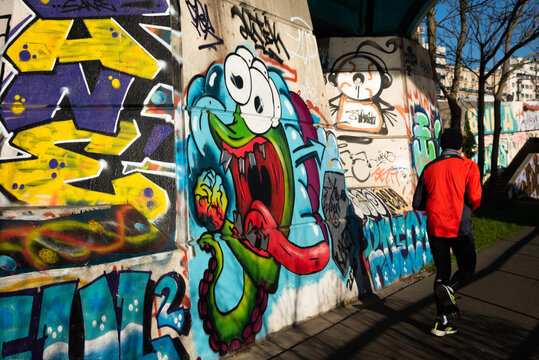 Charenton-le-Pont, France - January 10, 2021: Crazy workout. Urban art and healthy lifestyle in Parisian suburbs. Graffiti on bridge over Marne river; jogging man. Val-de-Marne, Ile-de-France, France