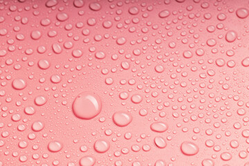 large drops of water and small ones on the pink surface are randomly arranged