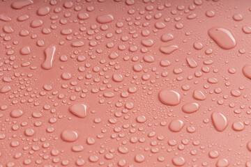 irregular shapes of water droplets on the pink surface. a backdrop of water droplets